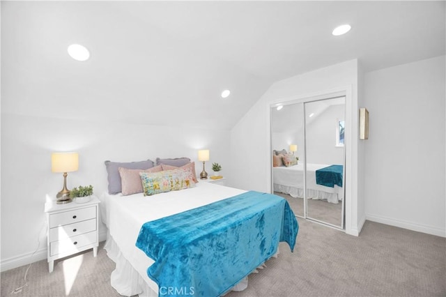 bedroom with lofted ceiling, baseboards, a closet, and light colored carpet