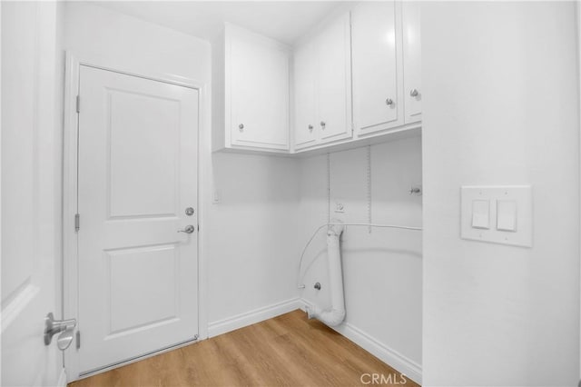 clothes washing area featuring cabinets and light wood-type flooring