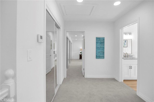 corridor featuring sink and light carpet