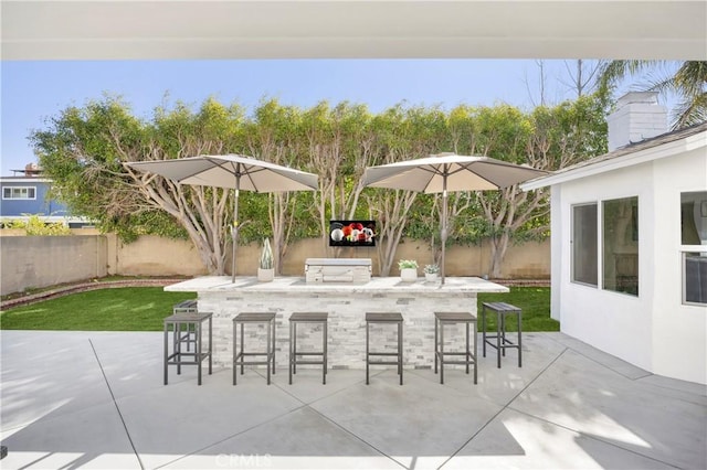 view of patio featuring grilling area, a fenced backyard, and outdoor wet bar