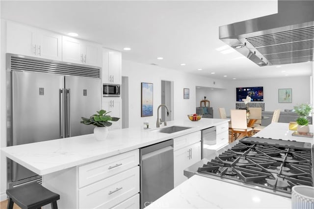 kitchen featuring white cabinetry, sink, a breakfast bar area, and built in appliances