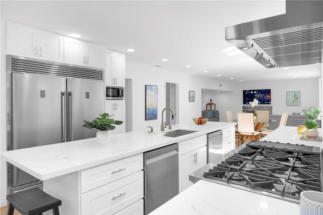 kitchen featuring white cabinets, a sink, a breakfast bar area, and built in appliances