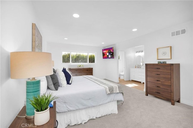 bedroom with light colored carpet, recessed lighting, visible vents, and ensuite bath