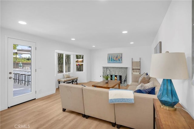 living room featuring a high end fireplace and light hardwood / wood-style flooring