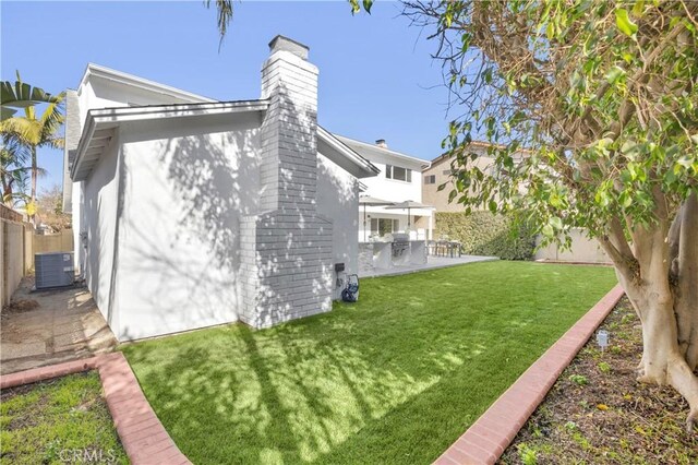 back of house featuring a yard, central AC, and a patio area