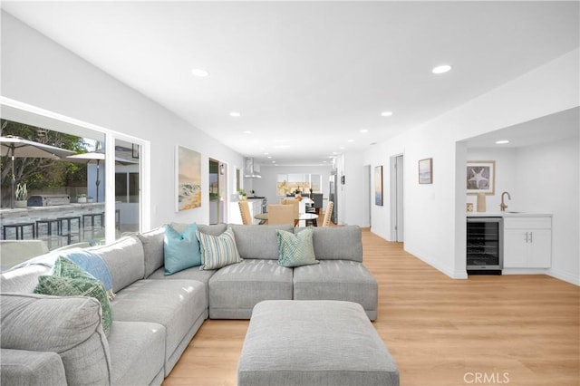 living room with wet bar, wine cooler, and light wood-type flooring