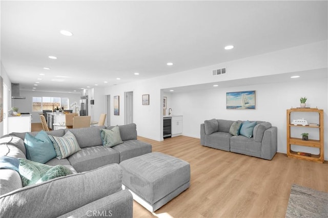 living area with wine cooler, indoor wet bar, light wood finished floors, recessed lighting, and visible vents