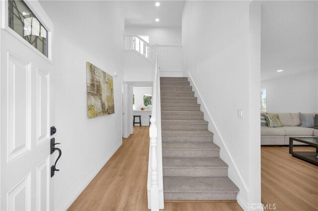 stairs featuring a towering ceiling and hardwood / wood-style floors