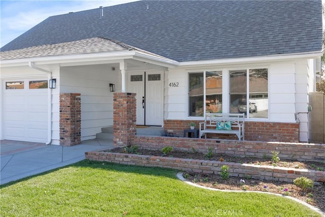 doorway to property featuring a garage, brick siding, a shingled roof, and a lawn