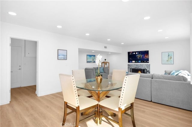 dining room with a premium fireplace and light hardwood / wood-style floors