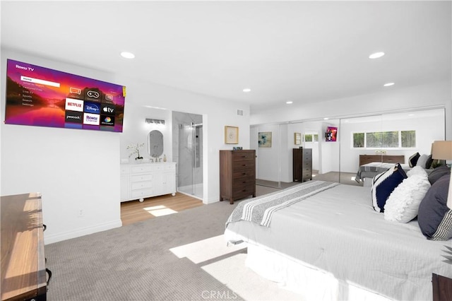 bedroom with recessed lighting, visible vents, light carpet, ensuite bath, and baseboards