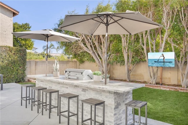 view of patio featuring fence, outdoor dry bar, and area for grilling