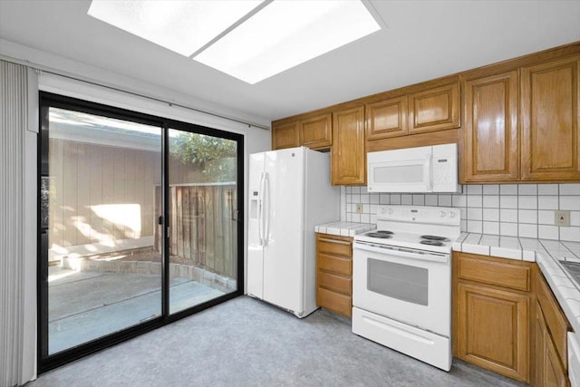 kitchen with tasteful backsplash, tile counters, and white appliances