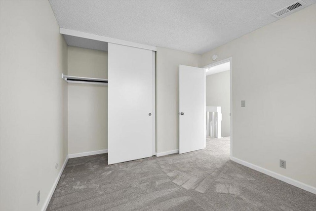 unfurnished bedroom featuring light carpet, a textured ceiling, and a closet