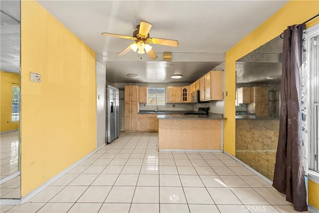 kitchen with appliances with stainless steel finishes, kitchen peninsula, light brown cabinets, and light tile patterned floors