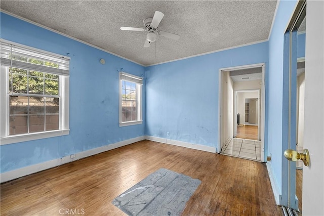 interior space featuring hardwood / wood-style flooring, ceiling fan, ornamental molding, and a textured ceiling