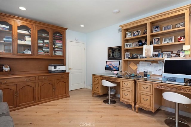 home office with built in desk and light wood-type flooring