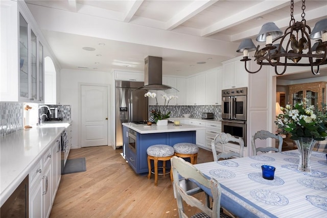 kitchen with island range hood, a kitchen breakfast bar, blue cabinets, and white cabinets