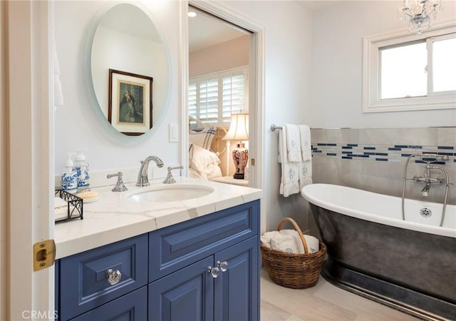 bathroom featuring vanity, a bath, tile walls, and a healthy amount of sunlight