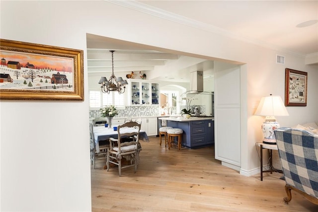 interior space with a notable chandelier, beam ceiling, ornamental molding, and light wood-type flooring