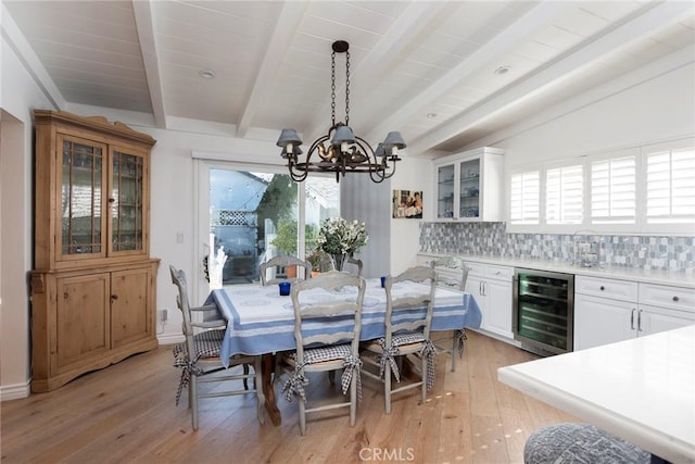 dining space with lofted ceiling with beams, beverage cooler, a healthy amount of sunlight, and light wood-type flooring