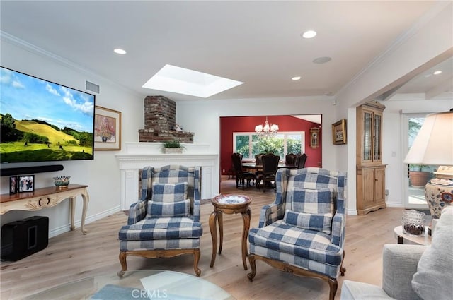 living area featuring a skylight, a notable chandelier, light hardwood / wood-style flooring, and ornamental molding