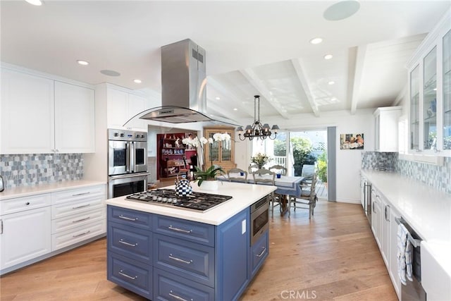 kitchen featuring blue cabinets, island range hood, light hardwood / wood-style flooring, stainless steel appliances, and white cabinets