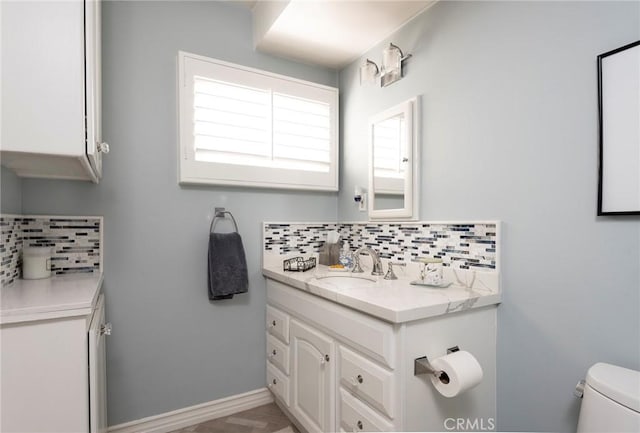 bathroom with vanity, toilet, and decorative backsplash