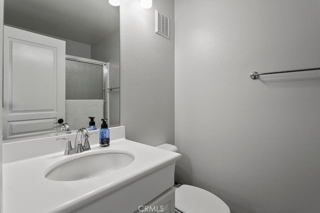 bathroom featuring vanity, an enclosed shower, and toilet