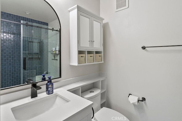 bathroom featuring vanity, a shower with door, and toilet