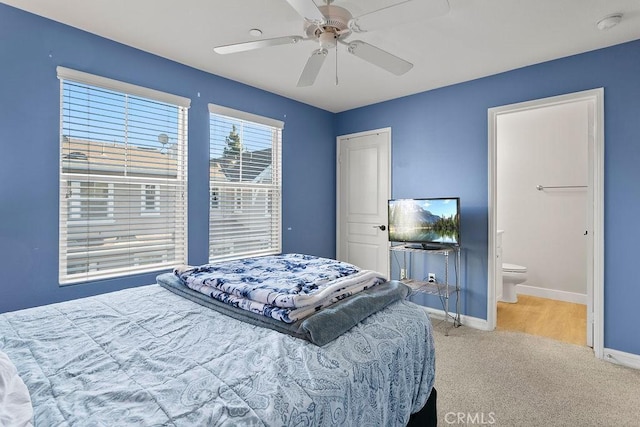 bedroom with ceiling fan, ensuite bath, and light carpet