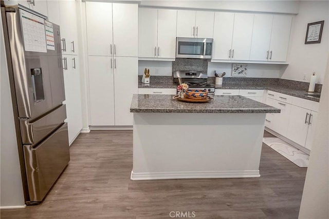 kitchen with stainless steel appliances, a kitchen island, dark wood-type flooring, and white cabinets