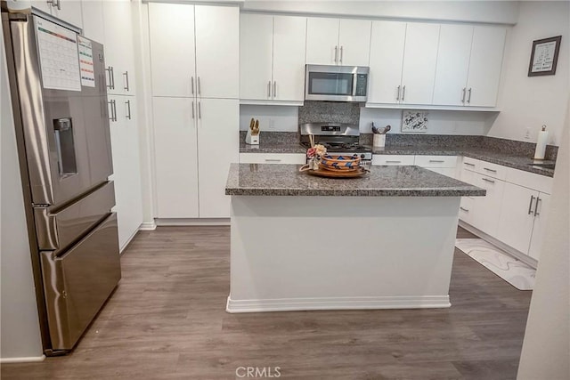 kitchen featuring white cabinetry, appliances with stainless steel finishes, dark hardwood / wood-style flooring, and a center island