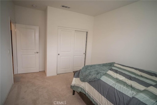 bedroom with light colored carpet and a closet