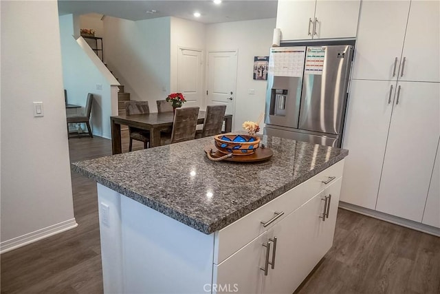 kitchen featuring dark hardwood / wood-style floors, stainless steel fridge, a center island, and white cabinets