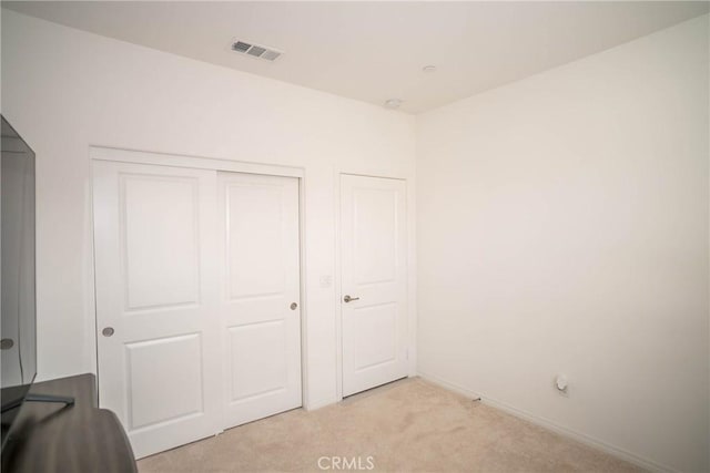 unfurnished bedroom featuring light colored carpet and a closet