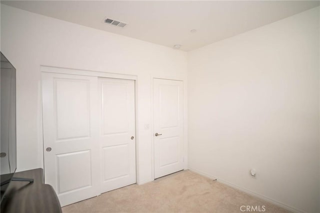 unfurnished bedroom with light carpet and a closet