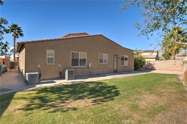 rear view of property featuring a yard and central air condition unit