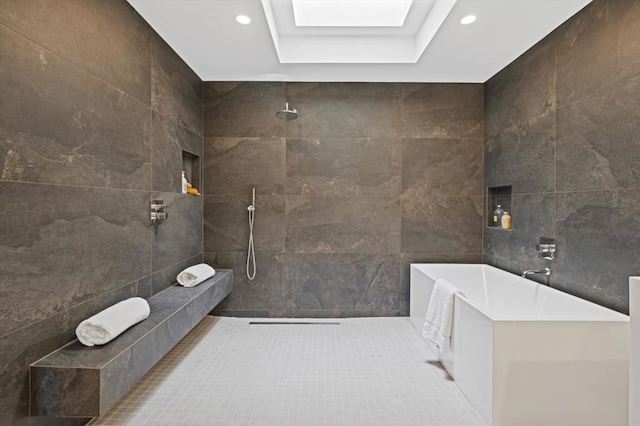 bathroom featuring shower with separate bathtub, a skylight, tile walls, a raised ceiling, and tile patterned floors