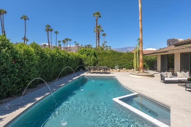 view of pool with a mountain view, a patio area, pool water feature, and an in ground hot tub