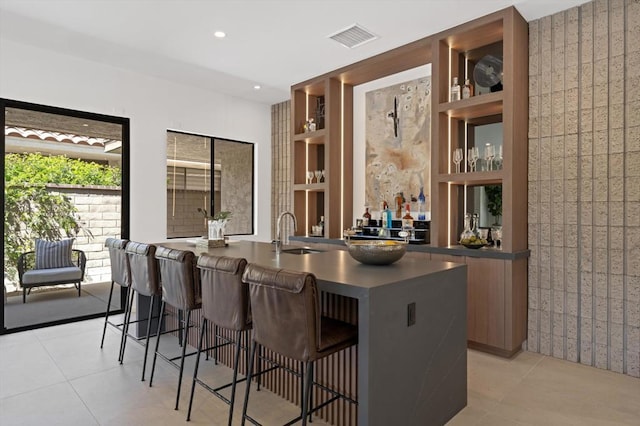 bar with sink, light tile patterned floors, and built in features