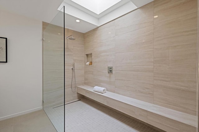 bathroom featuring tile patterned floors, a skylight, and a tile shower