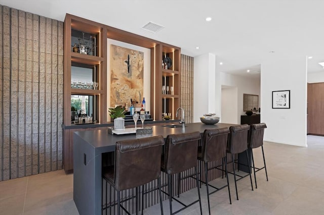 bar featuring sink, light tile patterned floors, and built in features