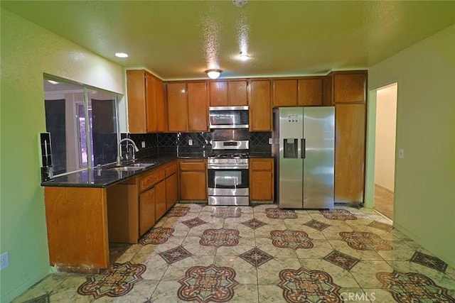 kitchen featuring brown cabinetry, appliances with stainless steel finishes, decorative backsplash, and a sink