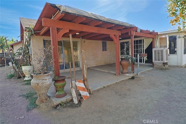 rear view of house featuring cooling unit, a patio area, and stucco siding