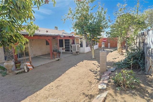 rear view of house with a patio area, a fenced backyard, central AC, and stucco siding