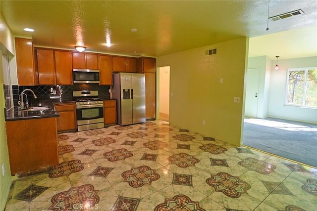 kitchen with appliances with stainless steel finishes, dark countertops, visible vents, and backsplash