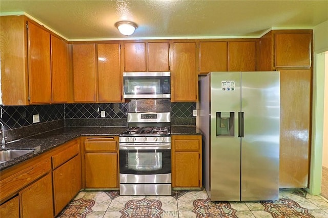 kitchen featuring appliances with stainless steel finishes, a sink, and brown cabinets