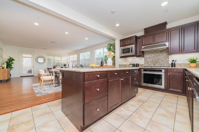 kitchen featuring light tile patterned floors, backsplash, a healthy amount of sunlight, and appliances with stainless steel finishes