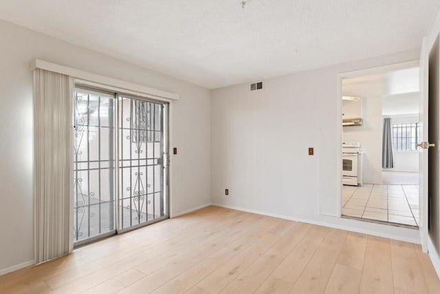 spare room featuring a textured ceiling and light hardwood / wood-style flooring